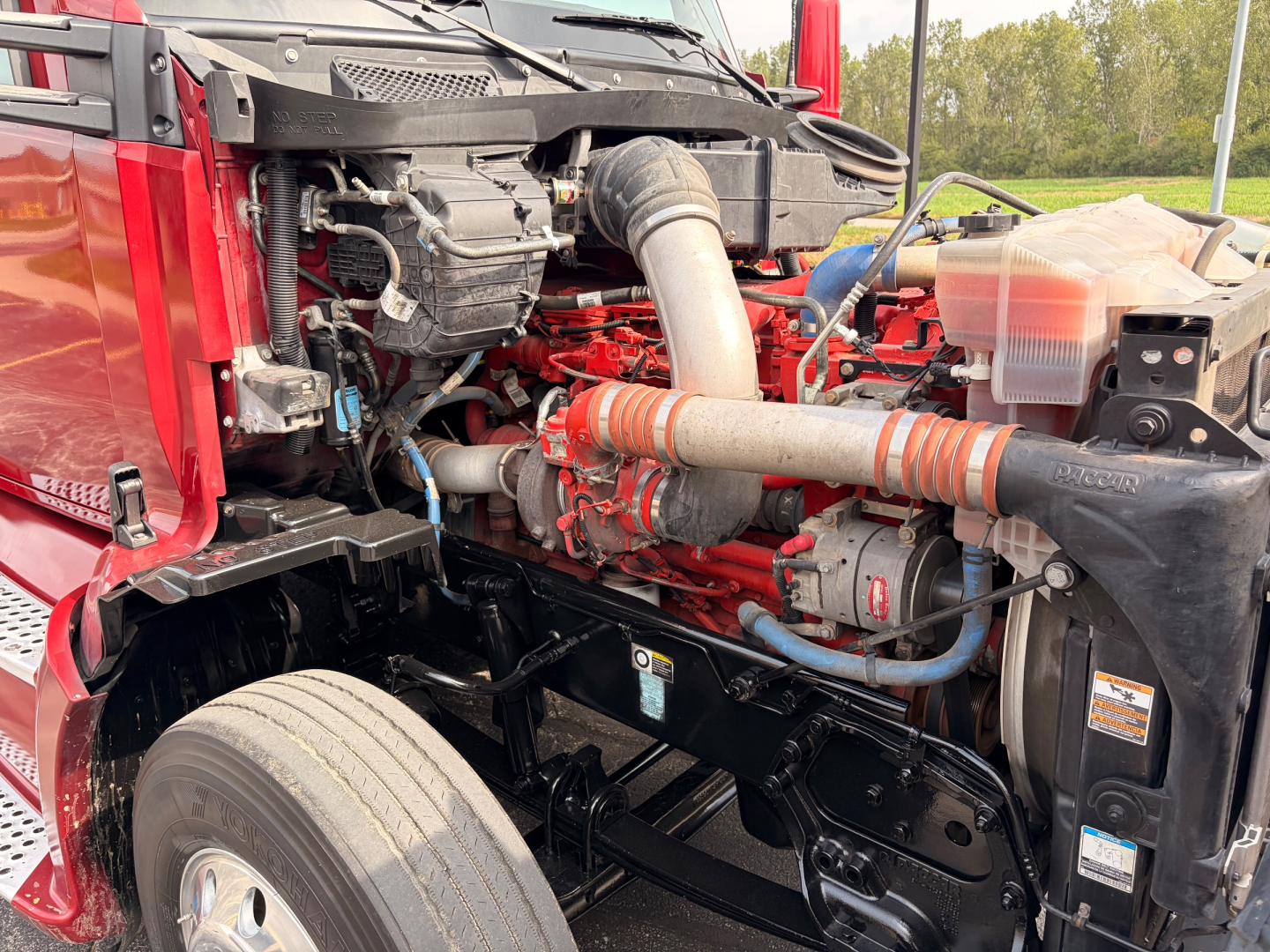 Kenworth T680 engine bay view showing large intercooler piping, red engine block, and front chassis components.
