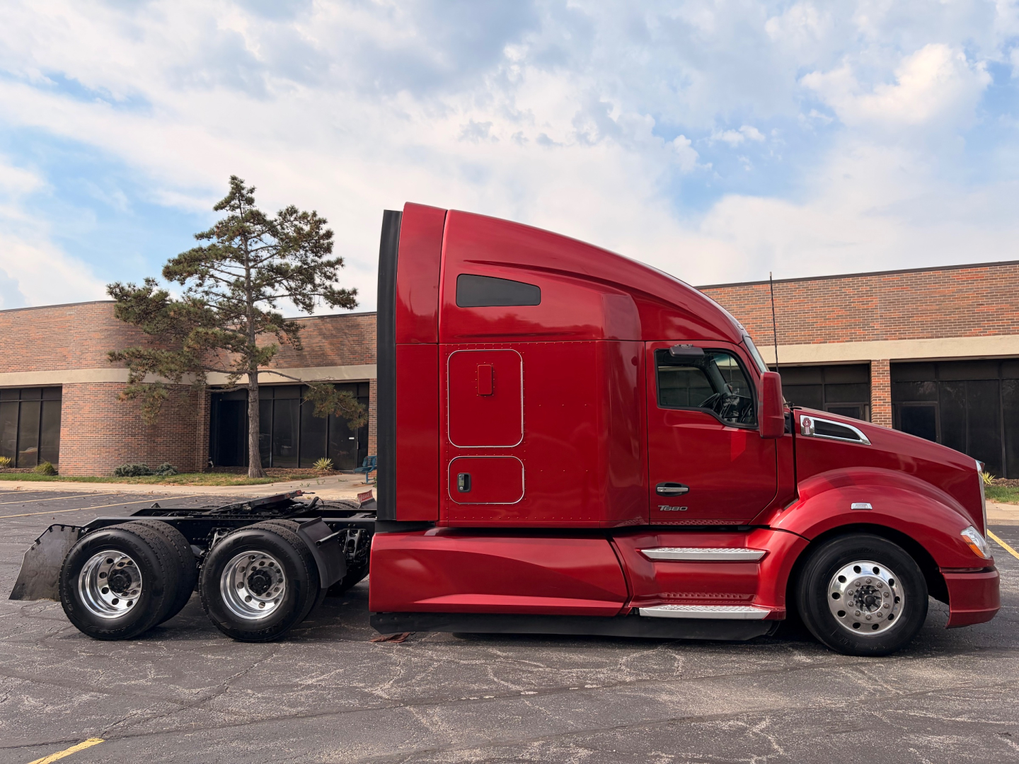 Side view of a red Kenworth T680 tractor with sleeper cab. No visible text on the cab exterior.