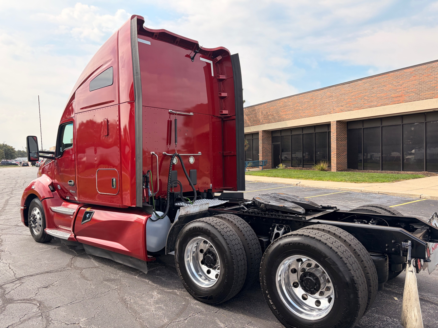 Kenworth T680 tractor cab rear view showing truck’s red body and dual rear axles with chrome wheels.