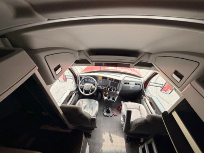 Kenworth T680 cab interior and dashboard view from doorway showing steering wheel, seats, and center console.