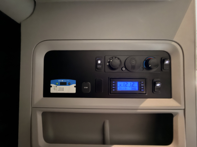 Kenworth T680 truck interior dashboard panel showing controls, digital display, and storage compartment.