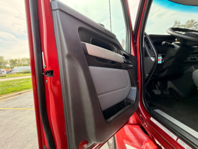 Vehicle interior: driver door open of a red 2022 Kenworth T680 with black and gray door panel.