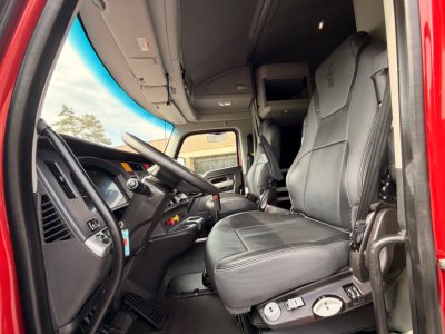 Kenworth T680 truck interior driver seat and dashboard view showing steering wheel, controls, and center console.