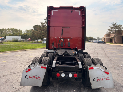 Rear view of a 2022 Kenworth T680 tractor chassis showing MHC mud flaps and rear lights with fifth wheel and dual rear axles.