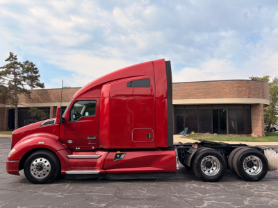 Kenworth T680 conventional sleeper truck side view showing red cab and chassis with sleeper cab, tandem rear axles, and fuel tanks.