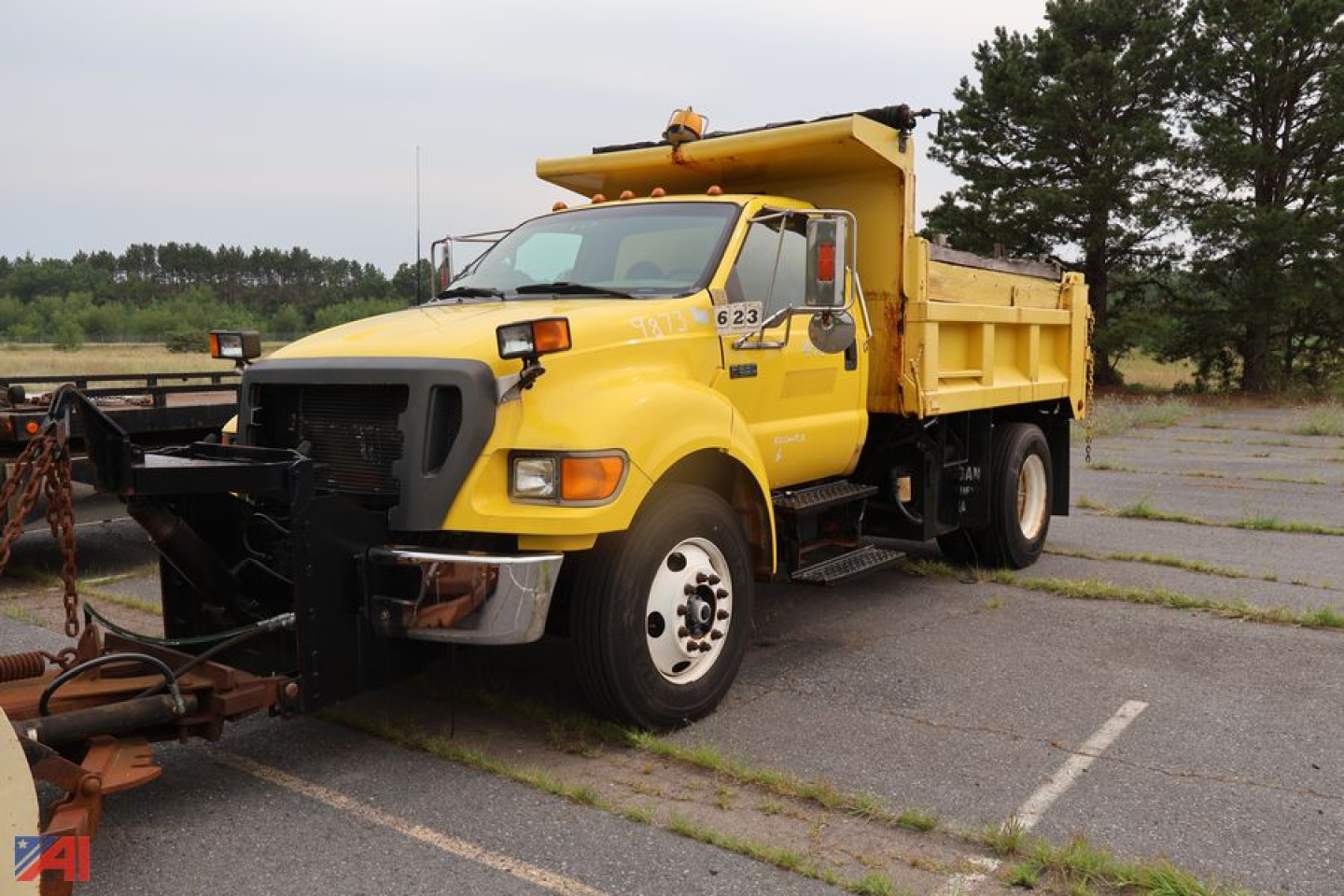 2005 Ford F650 Super Duty Dump Truck with Plow in yellow, front view, plow attachment on front, dump bed raised. Visible text includes '623' on cab door and 'FO' on side.
