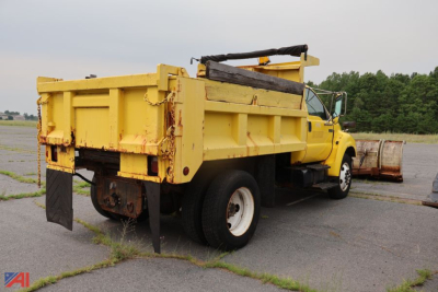 Dump truck with yellow dump bed and plow attachment visible, side and rear view
