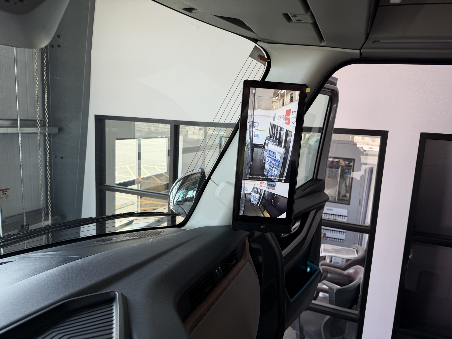 Cab interior of a Volvo VNL truck showing a mounted tablet display on the passenger side and rearview mirror reflections in the windshield.