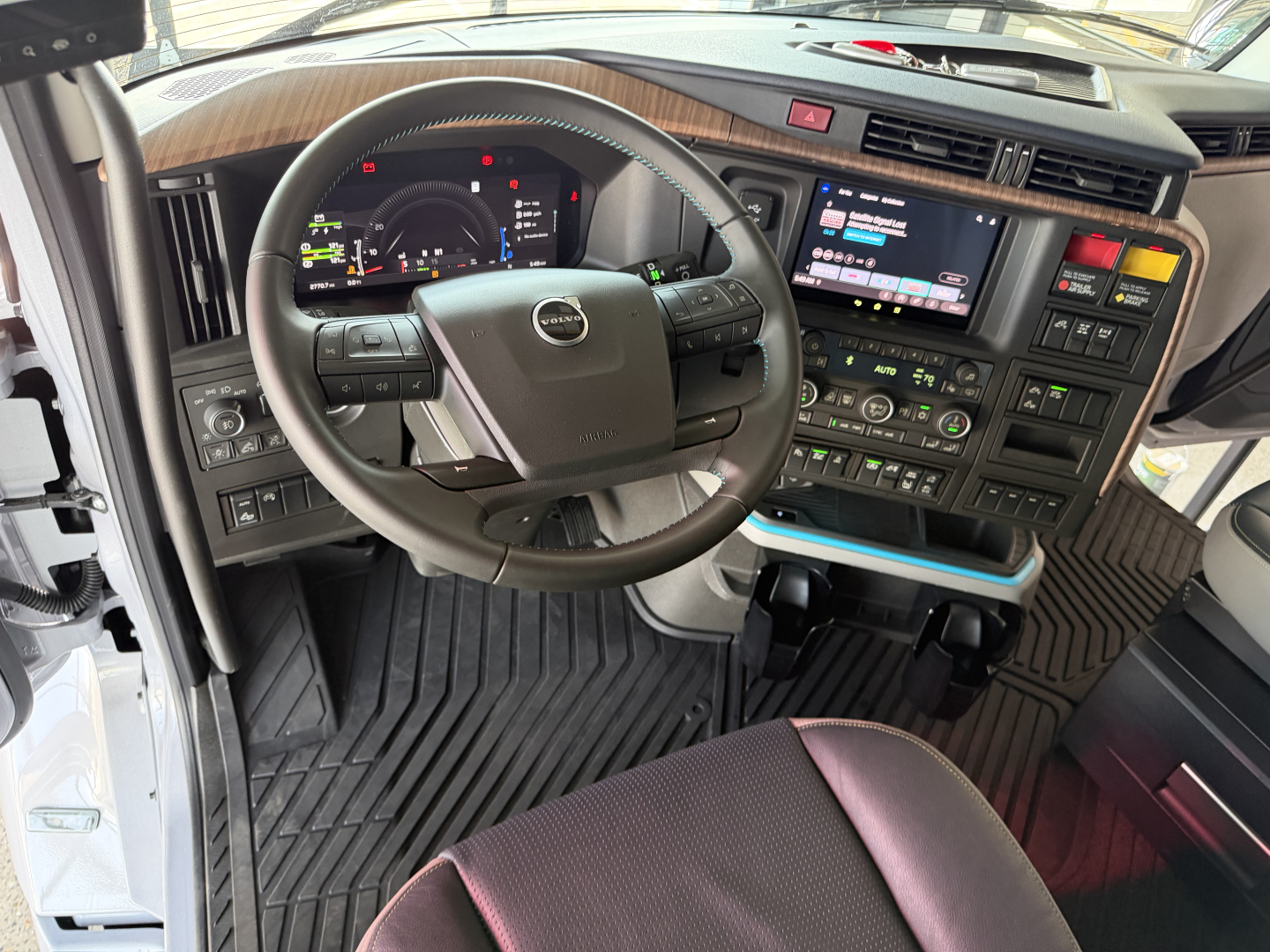 Volvo VNL64T860 truck interior showing steering wheel, dashboard with digital gauge cluster, center infotainment touchscreen, and control panels.