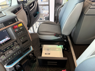 Volvo VNL64T860 sleeper cab interior showing driver seat and center console with dashboard controls and open storage drawer.