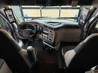 Volvo VNL64T860 truck interior showing dashboard, steering wheel, multiple screens, and center console with controls.