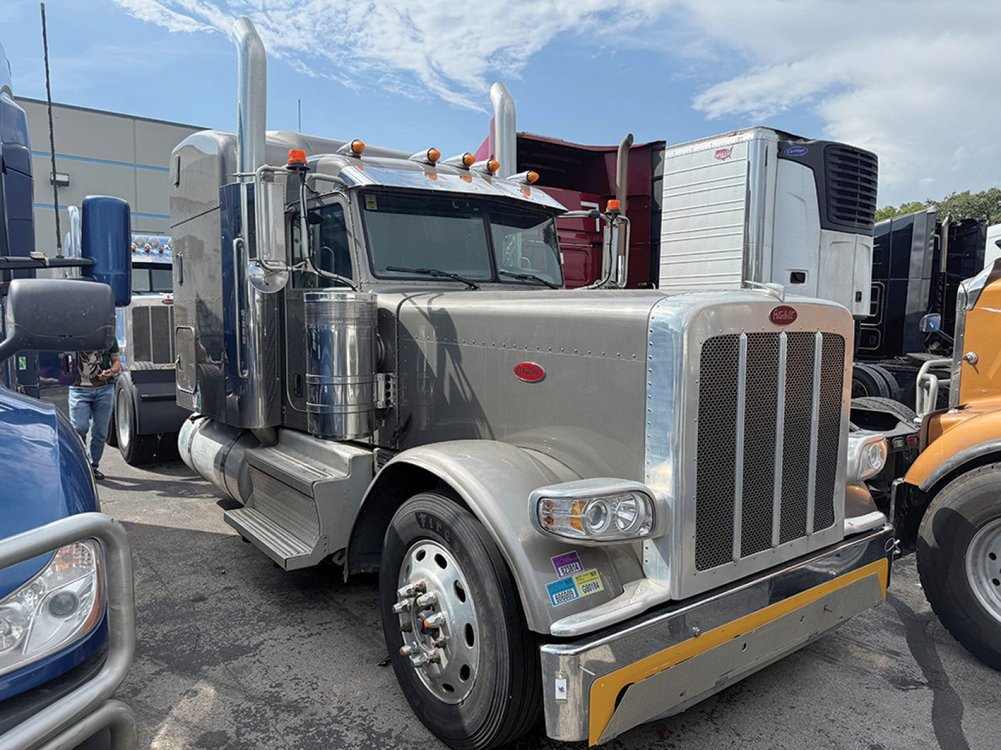 Peterbilt 389 UltraCab Extended Hood tractor-trailer in gray with chrome accents, front bumper guard, dual exhaust stacks, and large grille.