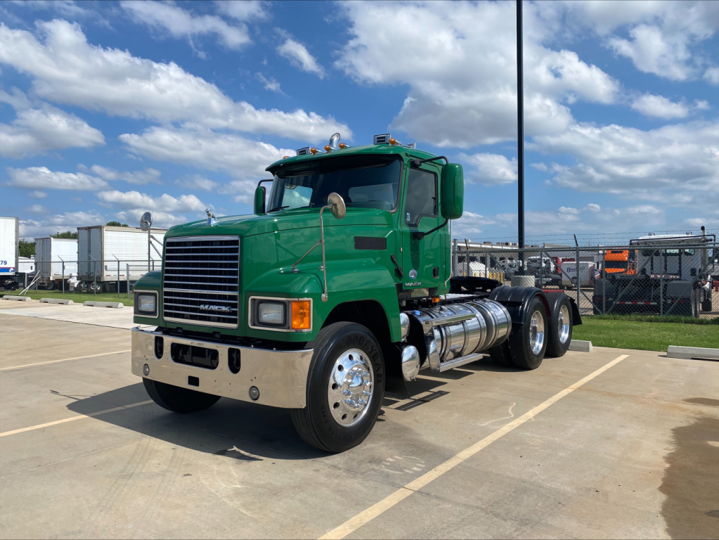 Green 2018 Mack CHU613 conventional daycab truck in a parking lot showing front grille and side fuel tanks.