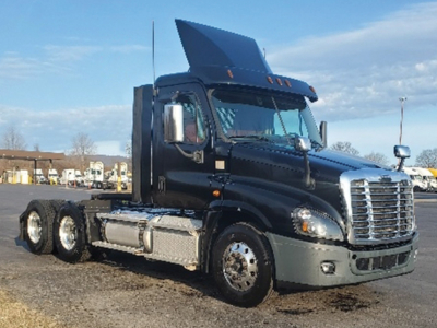 Truck cab and chassis showing Freightliner Cascadia style front with raised hood, black exterior, chrome grille, dual rear axles, and side fuel tanks.