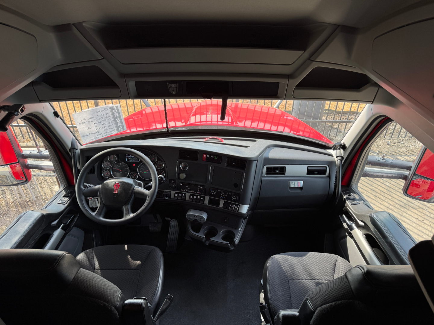 Kenworth T680 cockpit/driver area inside cab showing steering wheel, dashboard, and center consoles.