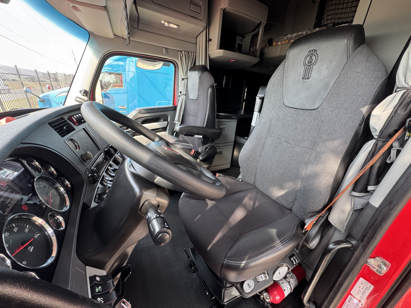 Kenworth T680 truck interior showing driver seat, steering wheel, and dashboard with gauges.