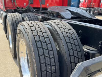 Kenworth T680 chassis with dual rear axles and tires in view; side of trailer cab behind showing wheels and rims.