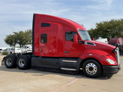 Red 2022 Kenworth T680 semi truck side view showing sleeper cab with black side skirt and dual rear axles.