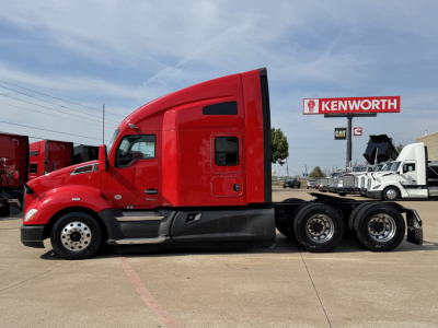 Kenworth T680 sleeper tractor in red, side view with wheel set and chassis, Kenworth sign in background.