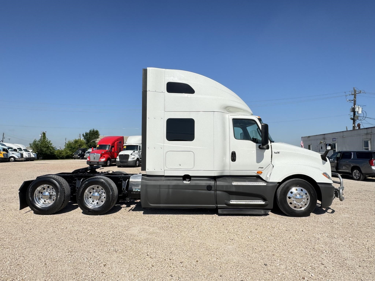 Truck cab side view of a 2020 International LT with sleeper, plastic white cab, dual rear axles, visible chrome wheels.