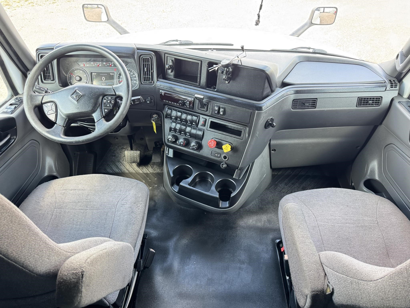 Interior of a 2020 International LT cab showing steering wheel, dashboard with controls, center console, and two front seats.