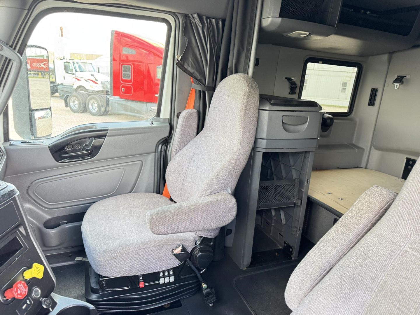 Cab interior of a 2020 International LT truck showing driver's seat, passenger seat, and sleeper area with storage cabinet and countertop.