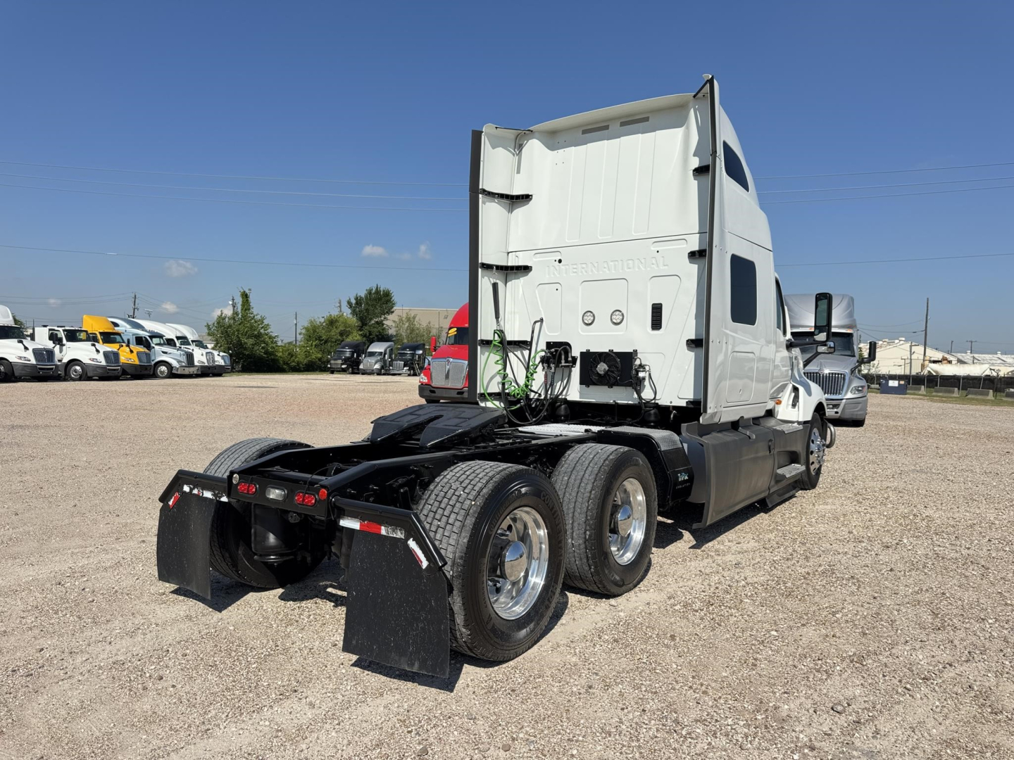 Truck rear view showing sleeper cab, dual rear axles, green hoses, and fender mud flaps. Visible text on cab includes no obvious branding.