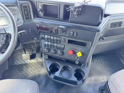 Truck interior dashboard of a 2020 International LT showing instrument cluster, center control panel, multiple switches, cup holders, and steering column.