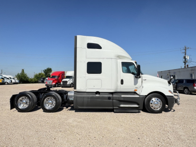 Truck cab side view of a 2020 International LT with sleeper, plastic white cab, dual rear axles, visible chrome wheels.