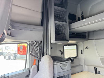 Cab interior of a 2020 International LT truck showing overhead sleeper area, storage compartments, and window with seat in view.