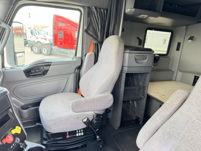 Cab interior of a 2020 International LT truck showing driver's seat, passenger seat, and sleeper area with storage cabinet and countertop.