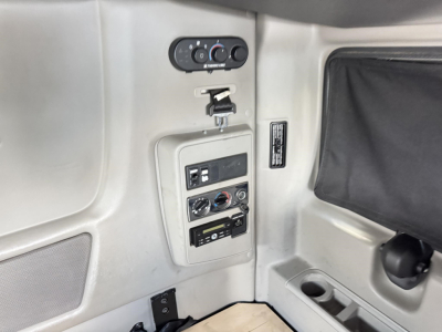 Dashboard panel in a 2020 International LT sleeper showing control switches, vents, and cup holder; includes circular gauges and a small panel with labeled controls.