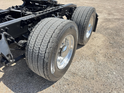 Dual rear truck axles with large tires and chrome wheels on a heavy-duty chassis, showing wheel rims and suspension components.