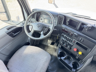 Truck interior showing steering wheel with instrument cluster, center console with controls and cup holders