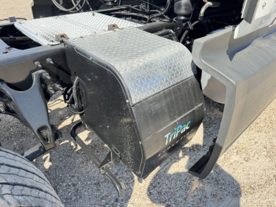 Truck side view showing aluminum diamond plate toolbox and Tripac label on black fender box near front wheel well