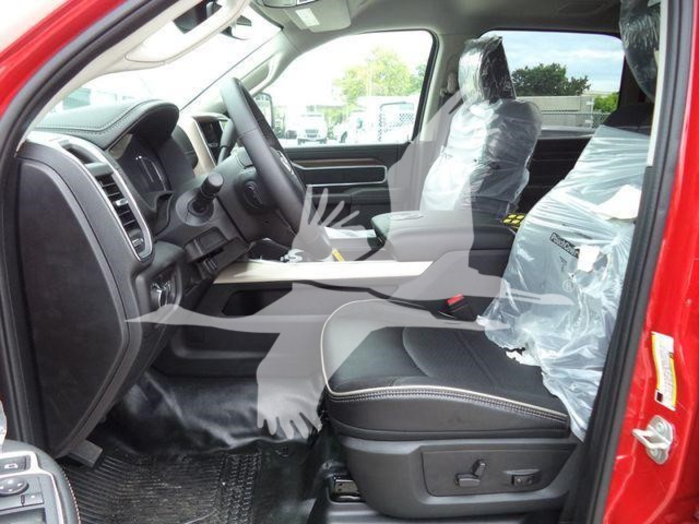 Ram truck interior with driver seat and front passenger seat wrapped in plastic. Dashboard and steering wheel visible. Front door sill and pedals visible.