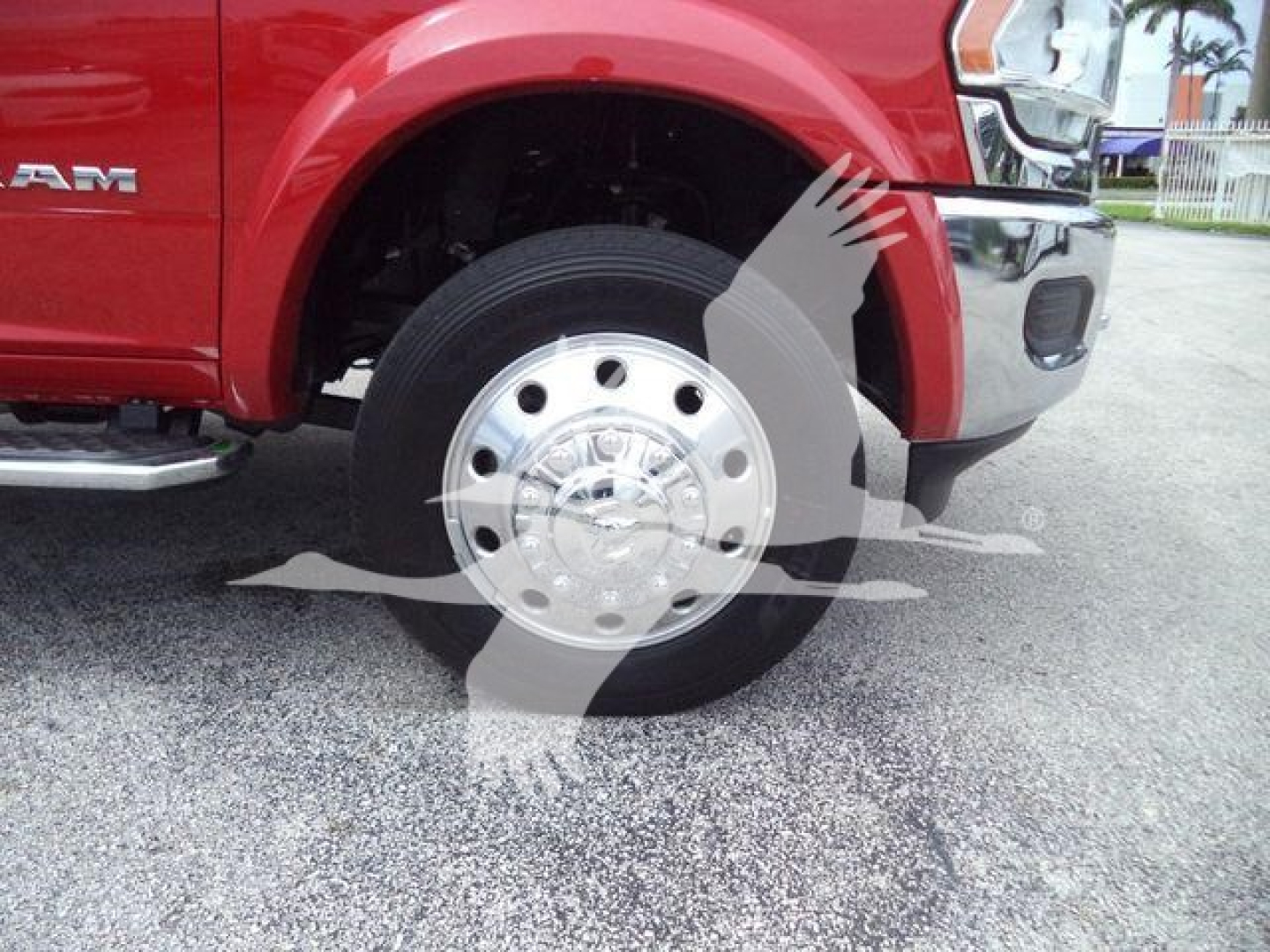 Ram pickup front wheel and tire assembly with chrome hubcap; partial front fender and bumper of red 2024 Ram Laramie truck.