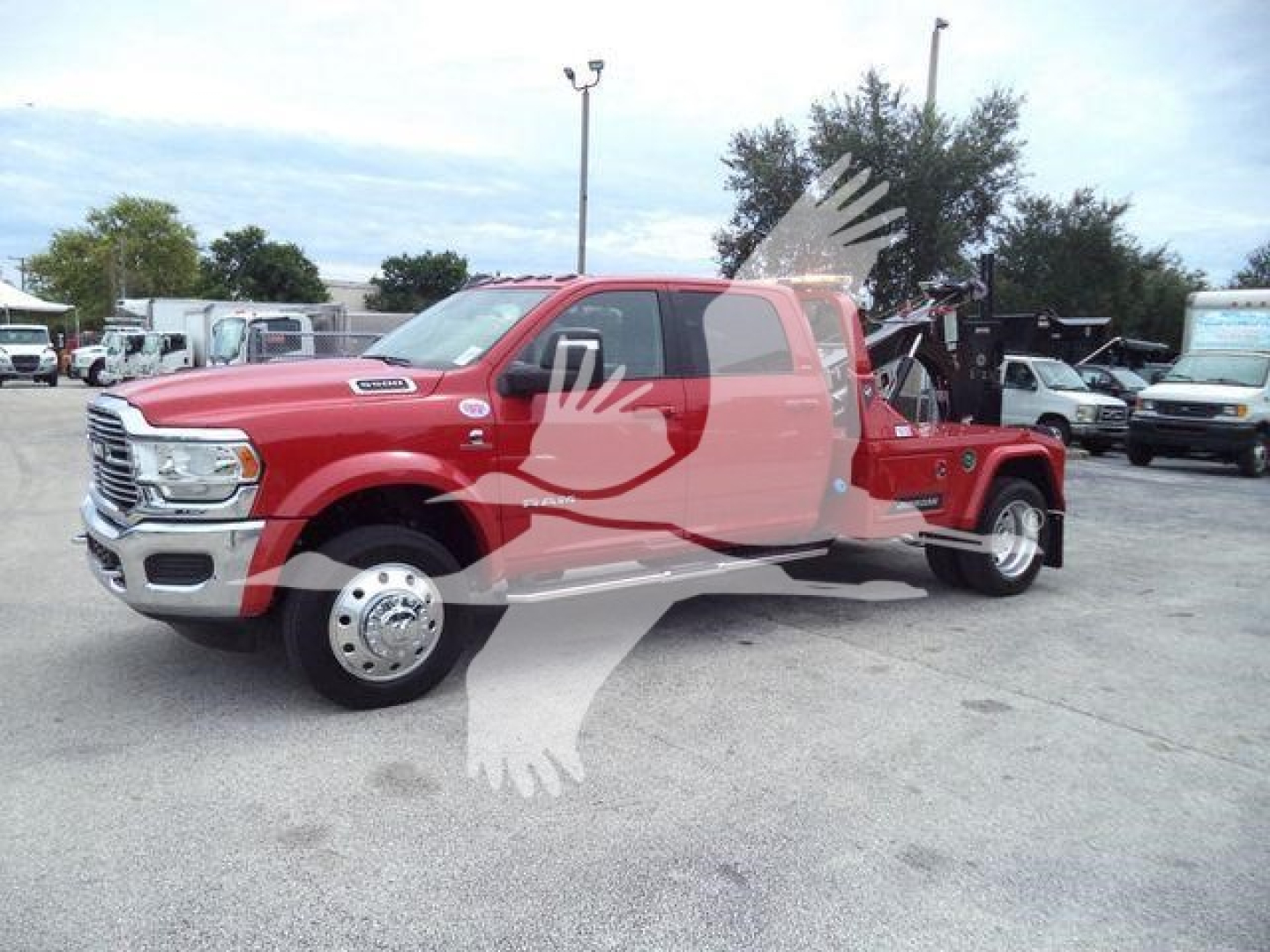 Truck with a red Ram tow truck body in a parking lot, front view showing chrome grille and dual rear wheels.