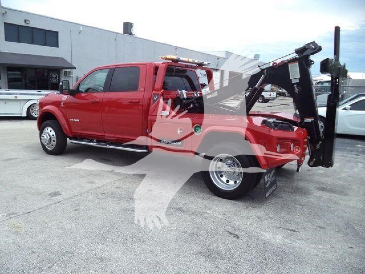 Ram pickup truck with a winch and hydraulic tow arm, red exterior, side view showing front doors and extended bed equipment.