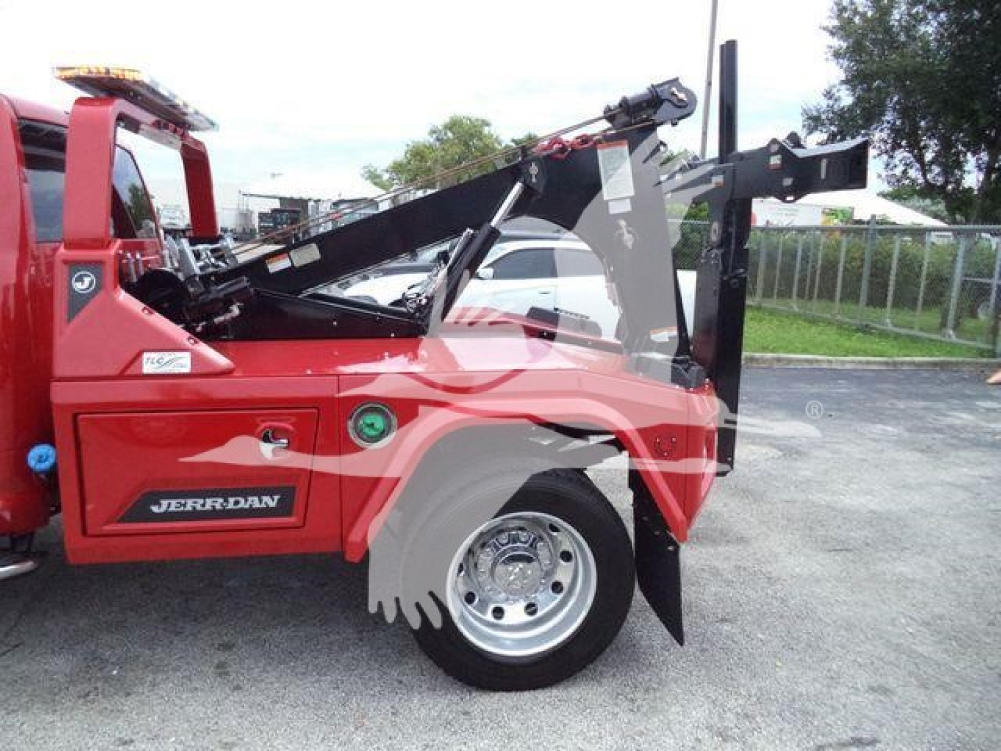 Ram truck with winch system and hydraulic arms visible in side view showing red body and Jerr-Dan branding.
