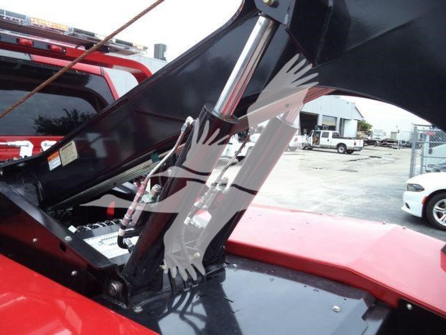 Truck engine bay with a raised hood showing hydraulic shocks and wiring near the engine compartment.
