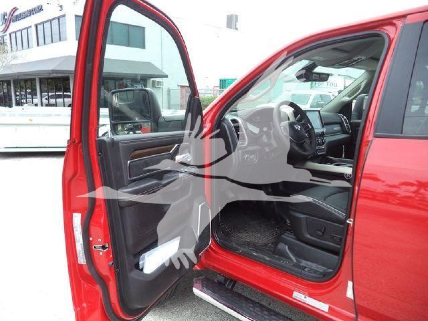 Ram truck interior view with open front passenger door showing dashboard and steering wheel; red exterior; left-side door open.