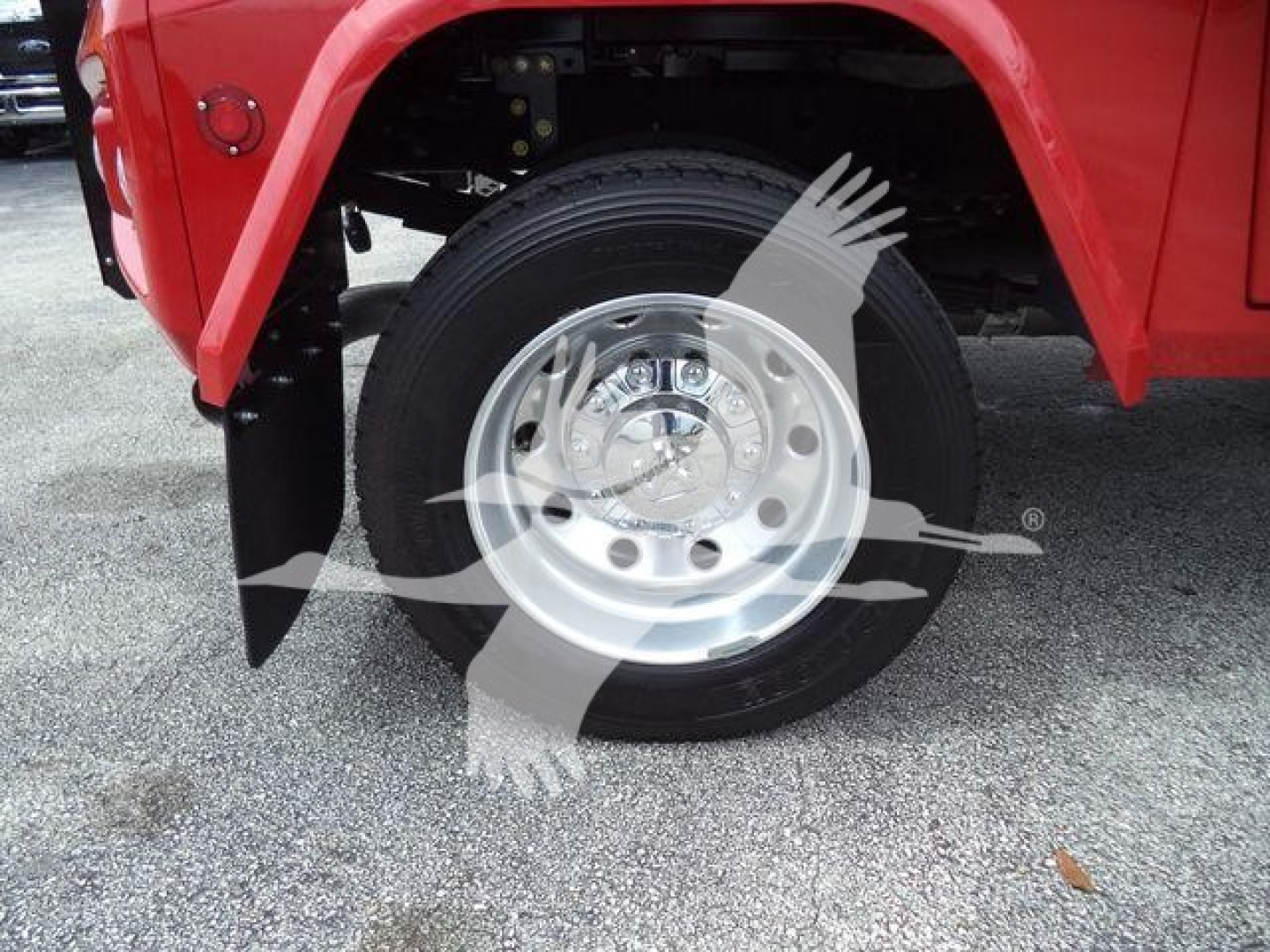 Ram truck wheel and fender showing chrome wheel, black tire, red body panel and wheel well.
