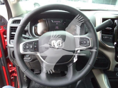 Ram steering wheel and dashboard inside 2024 Ram Laramie truck showing steering wheel controls and instrument cluster.