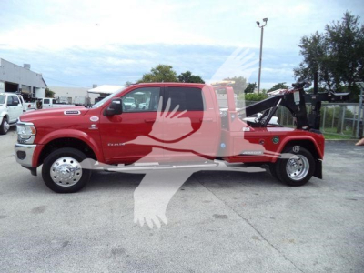Red 2024 Ram Laramie pickup truck with a winch-equipped flatbed/utility setup, side view showing extended cab and tow equipment.