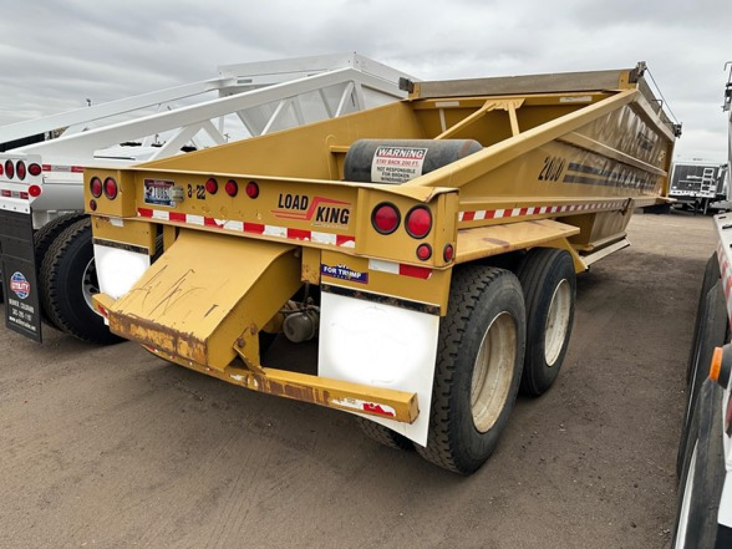 Load King originator bottom dump trailer viewed from rear-left showing yellow body and dual rear axles with Load King branding.