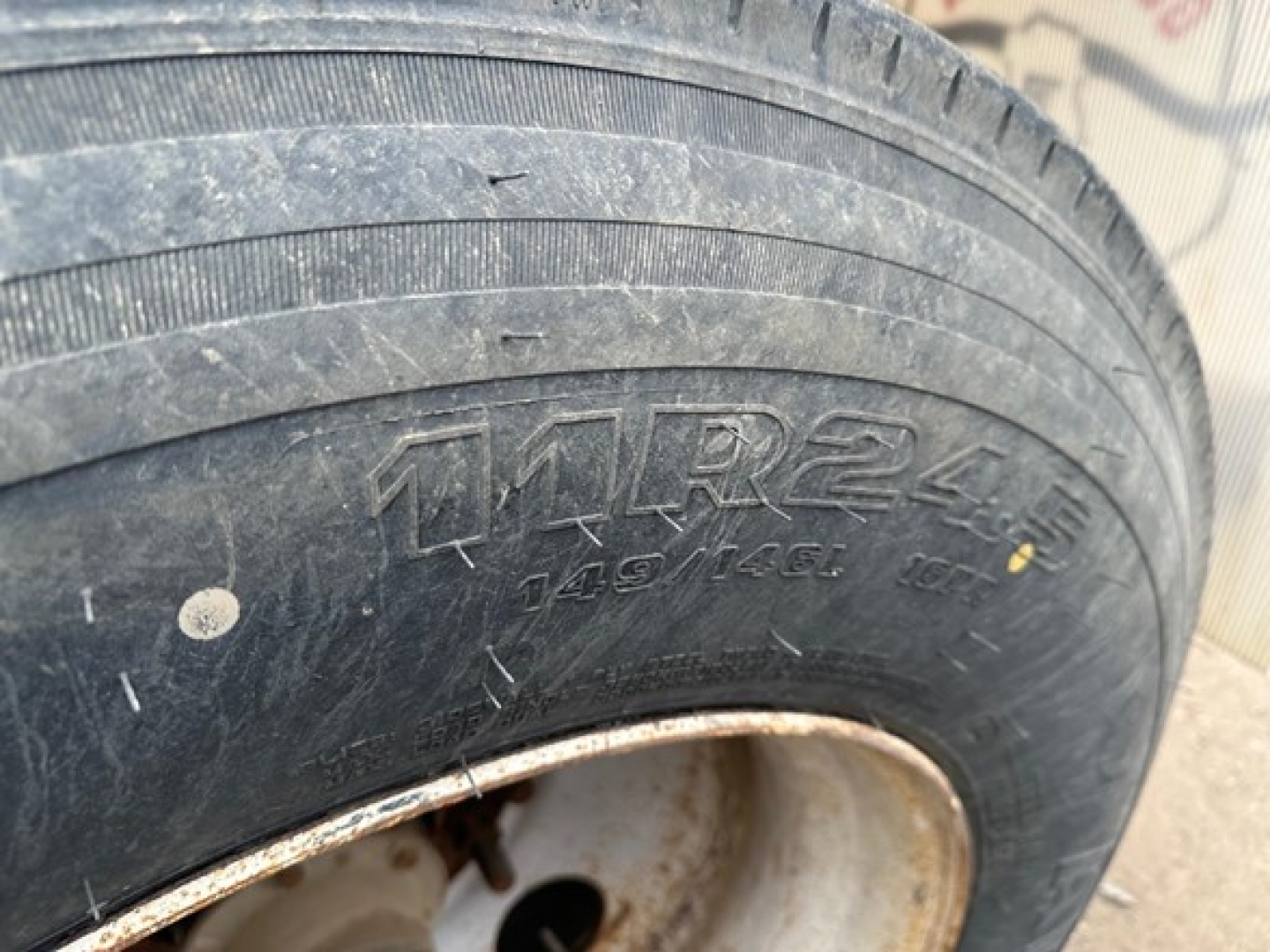 Trailer wheel with tire markings and rim; tread pattern visible with dirt and grime.