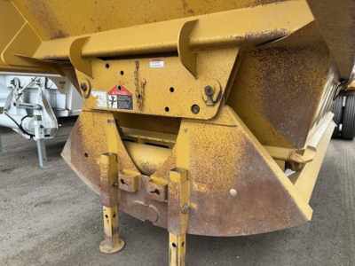 Bottom dump trailer hitch area with yellow paint and rust-like residues, showing frame supports and attachment points for a Load King Originator model.