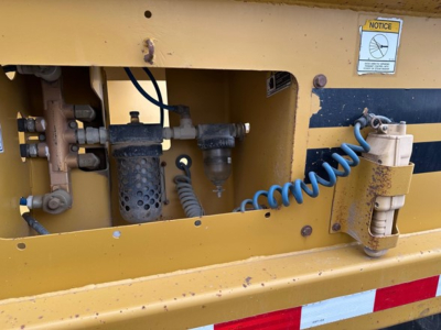 Part of a Load King originator bottom dump trailer showing hydraulic hoses and control components in the side access panel.