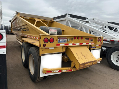 Load King originator bottom dump trailer in yellow showing rear view with dual rear axles and warning decals.